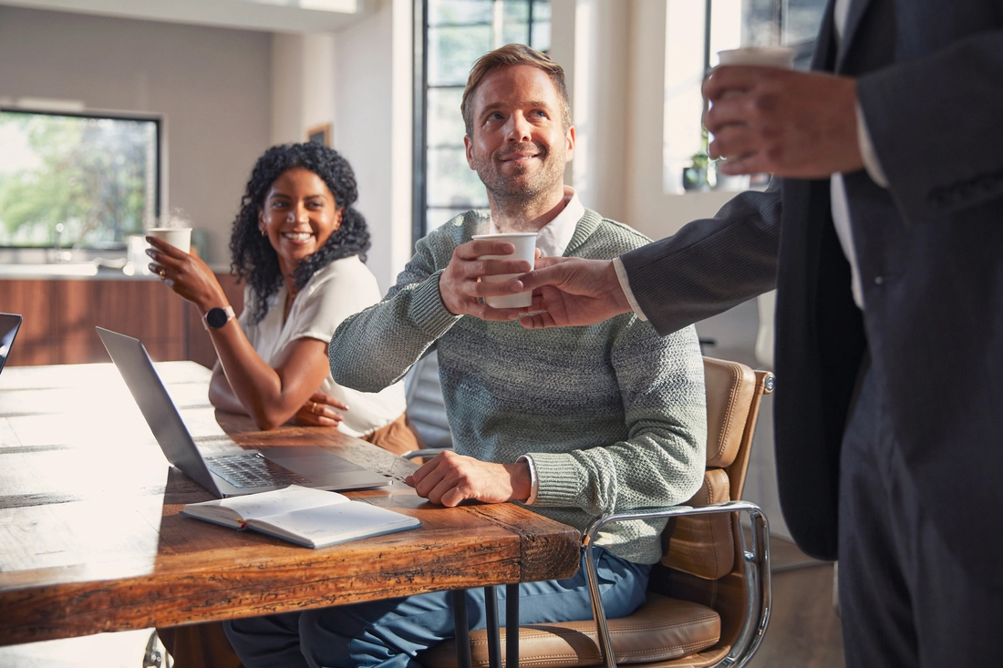 Colleagues sharing coffee in a bright meeting room.